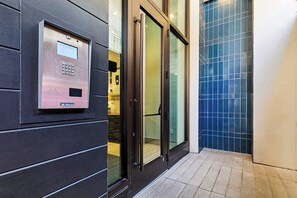 A modern elevator with a control panel, glass doors, and a tiled floor.