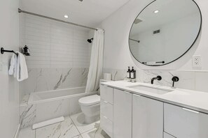 Et moderne badeværelse med badekar, toilet og håndvask.