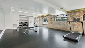 Ett modernt gym med löpband, träningsbänk och hantlar.