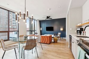 Ein modernes Wohnzimmer mit einem Glastisch, Korbstühlen, einer Couch und einem Flachbildfernseher.