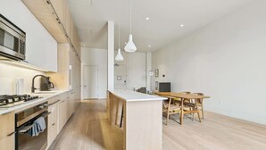 Une cuisine moderne dotée d’un îlot central, de planchers en bois et de luminaires suspendus.