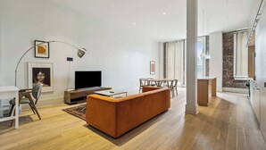 Un salon moderne avec un canapé, un téléviseur et un coin repas.