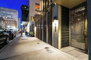 A nighttime street view of a building with a gated entrance, a signboard, and parked cars. - Prime 3BR Apartment in CBD w/ Balcony | Walk to Superdome (New Orleans)