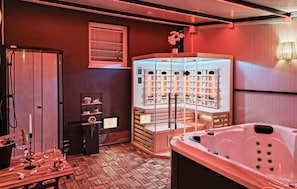 Un cuarto de spa con bañera de hidromasaje, camilla de masaje y sauna.