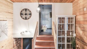 Ein Holzinnenraum mit Treppe, einer Uhr und einem Schrank mit Glastüren.