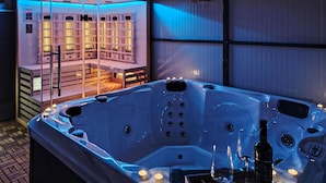 Ein Whirlpool mit Kerzen, einer Flasche und einem Glas.