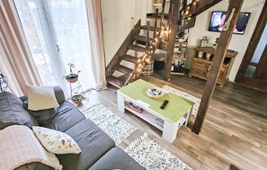 A modern living room with a grey sofa, a coffee table, and a staircase with string lights. - Lovely home in Veleskovec (Veleskovec)