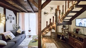 Un saló d'estar acollidor amb un sofà, una taula de centre i una escala decorada amb llums de garlandes.