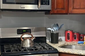 Une cuisine équipée d’une cuisinière à gaz, d’une bouilloire, d’un four à micro-ondes et d’un évier.