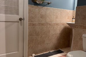 Une salle de bain avec des carreaux de couleur beige, une porte blanche et des toilettes blanches.