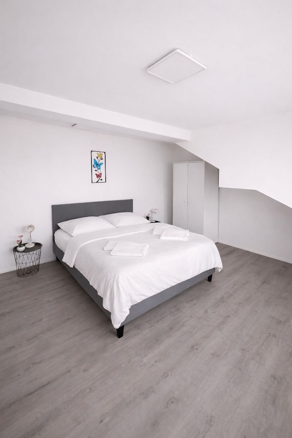 A modern bedroom with a bed, bedside tables, a wardrobe, and a ceiling light.