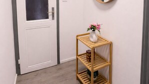 A hallway with a white door, a wooden shelf with a vase of flowers, and a round mirror on the wall. - Living on the Rhine: Central, spacious & by the cathedral! (Köln)