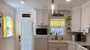 Una cocina con armarios blancos, un microondas, un lavavajillas y una estufa.