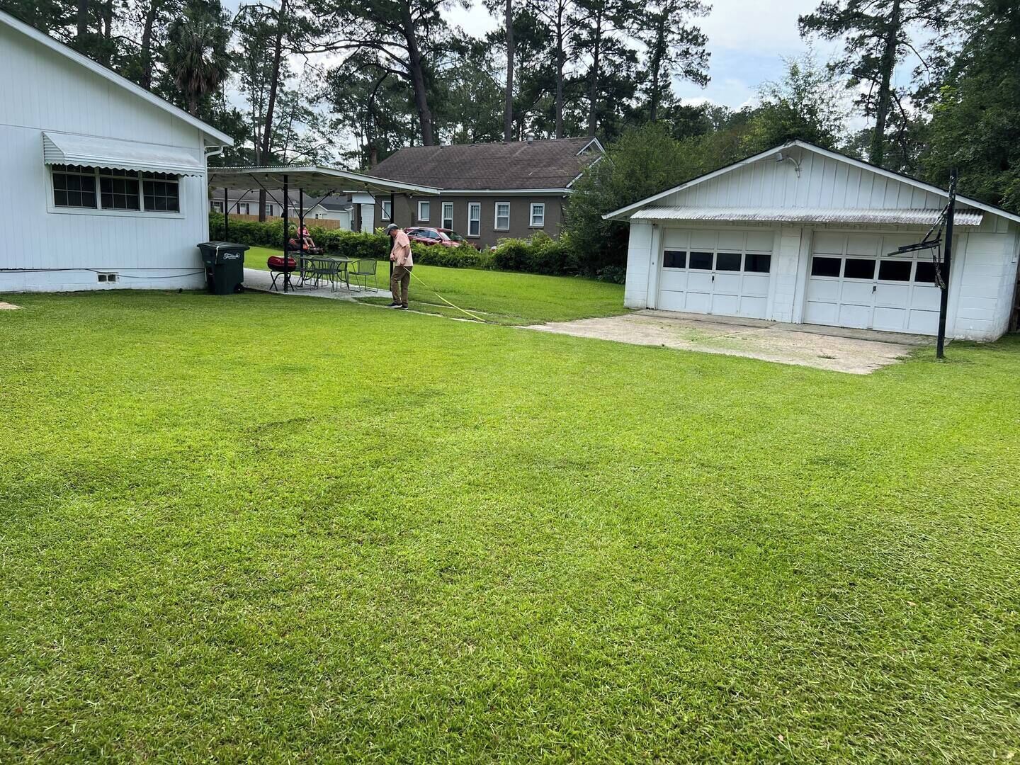 A residential area with a well-maintained lawn, a garage, and a small shed.