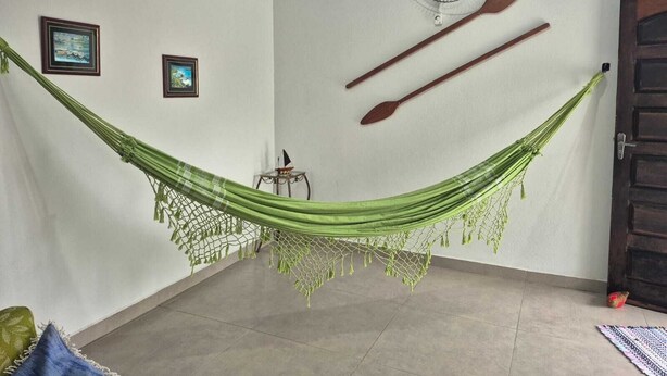 Una habitación con una hamaca, dos remos de madera, un ventilador y dos cuadros en la pared.