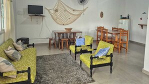 Una sala de estar con un sofá, sillas, un televisor, un ventilador y una mesa de comedor.