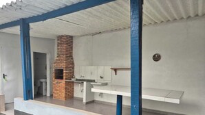 Un espacio al aire libre con cocina techada, horno de ladrillo, pileta y encimera.