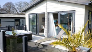 Une maison moderne dotée d’un jacuzzi, d’une terrasse et de portes-fenêtres coulissantes donnant sur un coin repas.