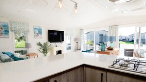 Une cuisine moderne dotée d’un grand îlot central, d’un téléviseur à écran plat et offrant une vue sur l’extérieur.