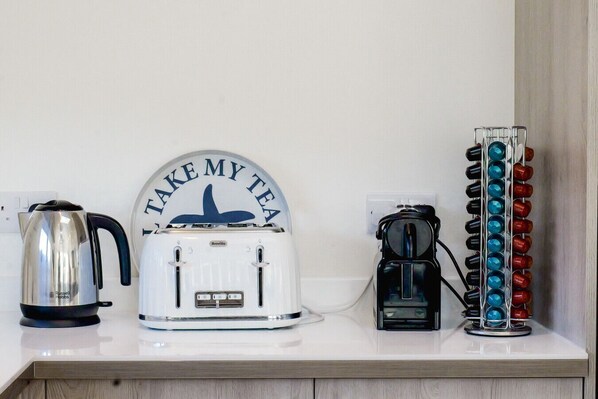 A kitchen counter with a kettle, a toaster, and a coffee maker.