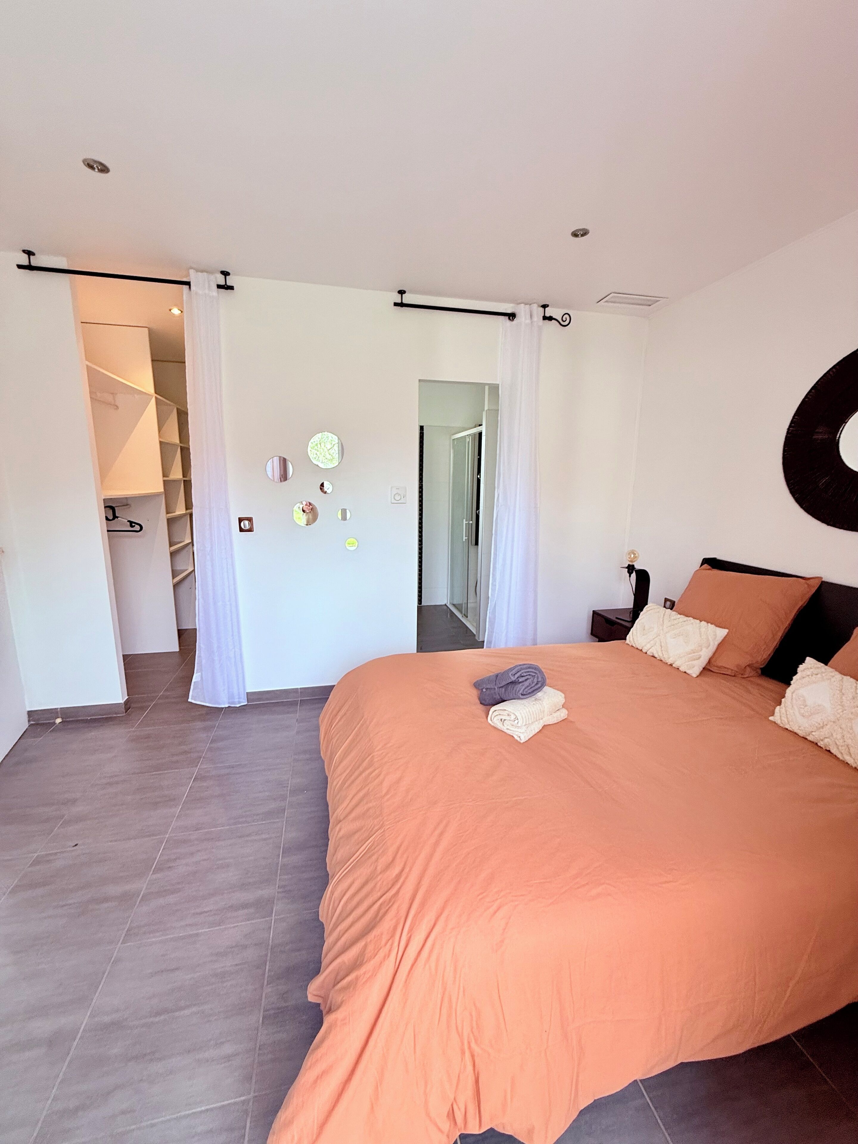 Ein Schlafzimmer mit einem großen Bett, einem begehbaren Kleiderschrank und einem Badezimmer mit einer Glasdusche.