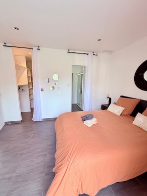 Ein Schlafzimmer mit einem großen Bett, einem begehbaren Kleiderschrank und einem Badezimmer mit einer Glasdusche.