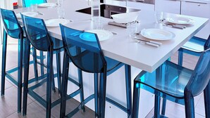Een moderne keuken met een centraal eiland, witte kasten en blauwe stoelen.