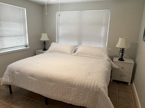 A bedroom with a large bed, two bedside tables with lamps, and two windows with blinds. - Ami Lido N ~ Private home two blocks to the beach (Bradenton Beach)