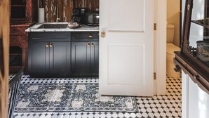 Een keuken met een zwart-wit betegelde vloer, een witte koelkast en een houten kast.