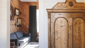 Een kamer met een houten vloer, een grote houten garderobe, een bank en een kamerbreed tapijt met een patroon.