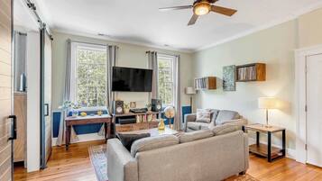 A living room with a sofa, TV, and a ceiling fan.