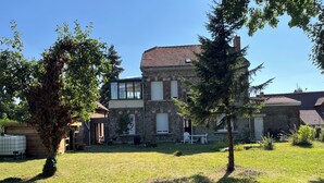 A stone building with a large yard, a wooden deck, and a small garden area.