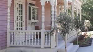 A pink house with a white porch and a small tree in front. - The Gilded Lady-King bed suite and private balcony (Pensacola)