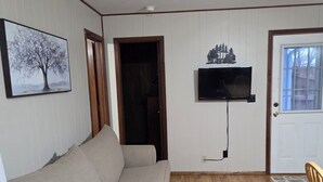 Un soggiorno con un divano, una televisione a parete e un pavimento in legno.