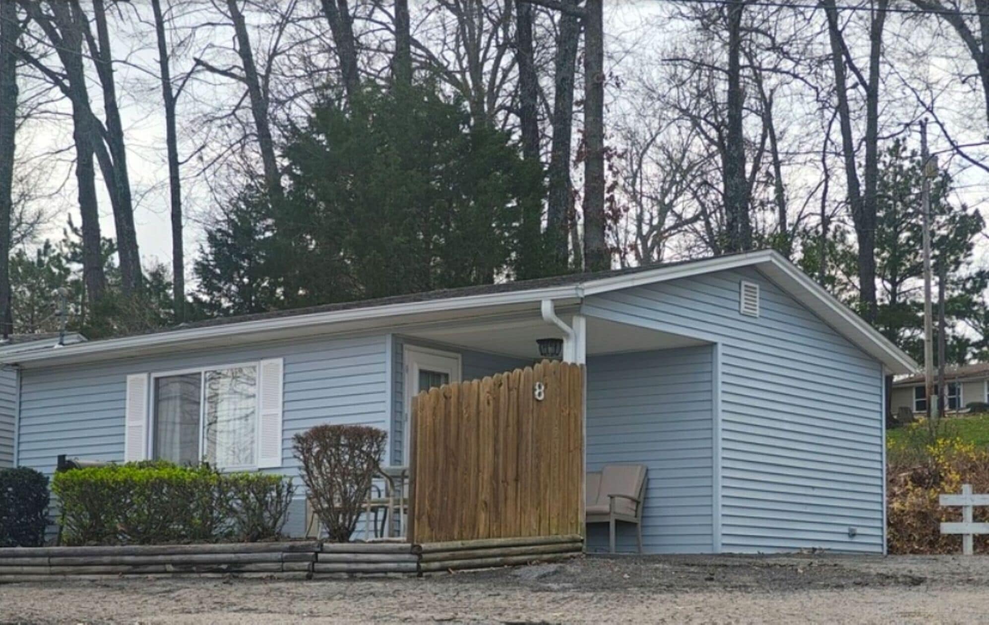 Ein eingeschossiges Haus mit Veranda, Holzzaun und der Hausnummer 8.