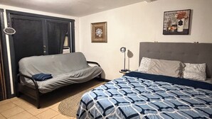 A bedroom with a bed, a sofa, a nightstand, and a wall-mounted lamp. - Cozy studio in Lancaster (Lancaster)