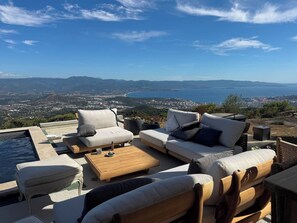A terrace with outdoor furniture, a pool, and a scenic view of a coastal city and mountains. - L'écrin de Paradis (ALATA)