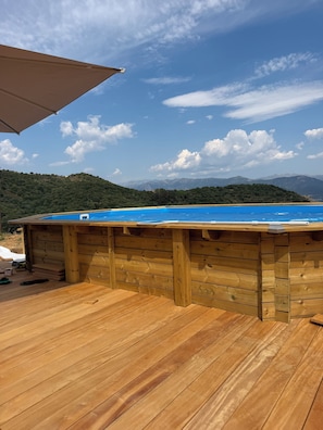 A wooden deck with a pool, a wooden fence, and a view of mountains. - L'écrin de Paradis (ALATA)