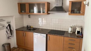 A compact kitchen with wooden cabinets, a built-in dishwasher, a sink, and a stove. - Cozy 1-Bedroom Apartment with Terrace and Pool in Bensafrim (Bensafrim)