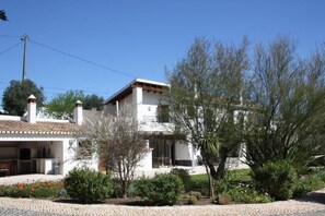 Ein zweistöckiges Haus mit Ziegeldach, einem Balkon und einem Garten mit verschiedenen Pflanzen und Blumen.