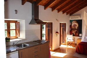 A kitchen with wooden beams, a large island with a sink, and a painting on the wall. - Cozy Studio with Balcony and Private Pool - Quinta Fronteira (Bensafrim)