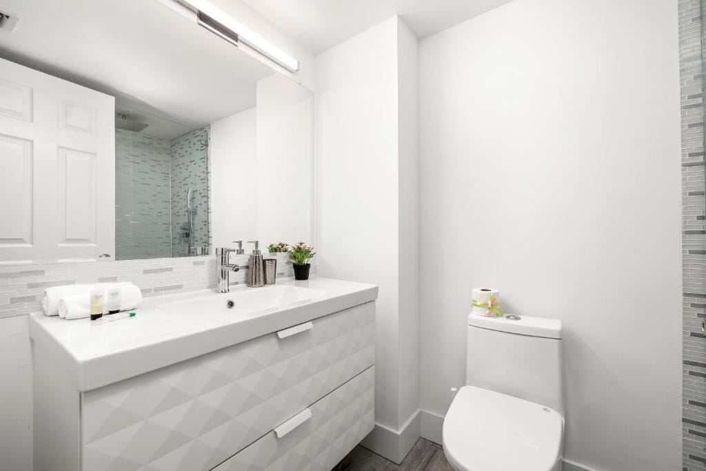 Un baño moderno con tocador blanco, inodoro y zona de ducha.