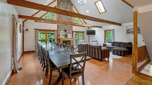 A spacious room with a large wooden dining table, a fireplace, a sofa, and a television.