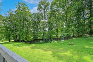 A grassy outdoor area with a swing set and a wooden deck.