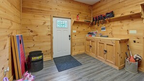 A wooden-paneled room with a door, a shelf with bags, and a storage cabinet.