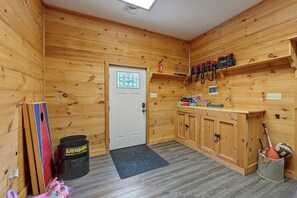 A wooden-paneled room with a door, a shelf with bags, and a storage cabinet. - ‘Shady Point Retreat’ w/ Hot Tub & Pickleball! (Killbuck)