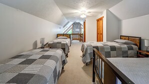 A bedroom with three beds, a ceiling fan, and a staircase leading to an upper level. - ‘Shady Point Retreat’ w/ Hot Tub & Pickleball! (Killbuck)