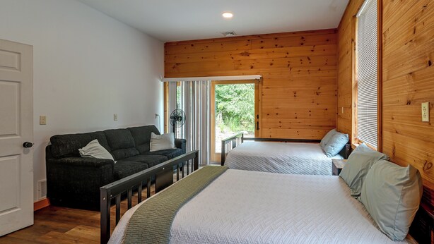 A room with a bed, a sofa, and a window with blinds.