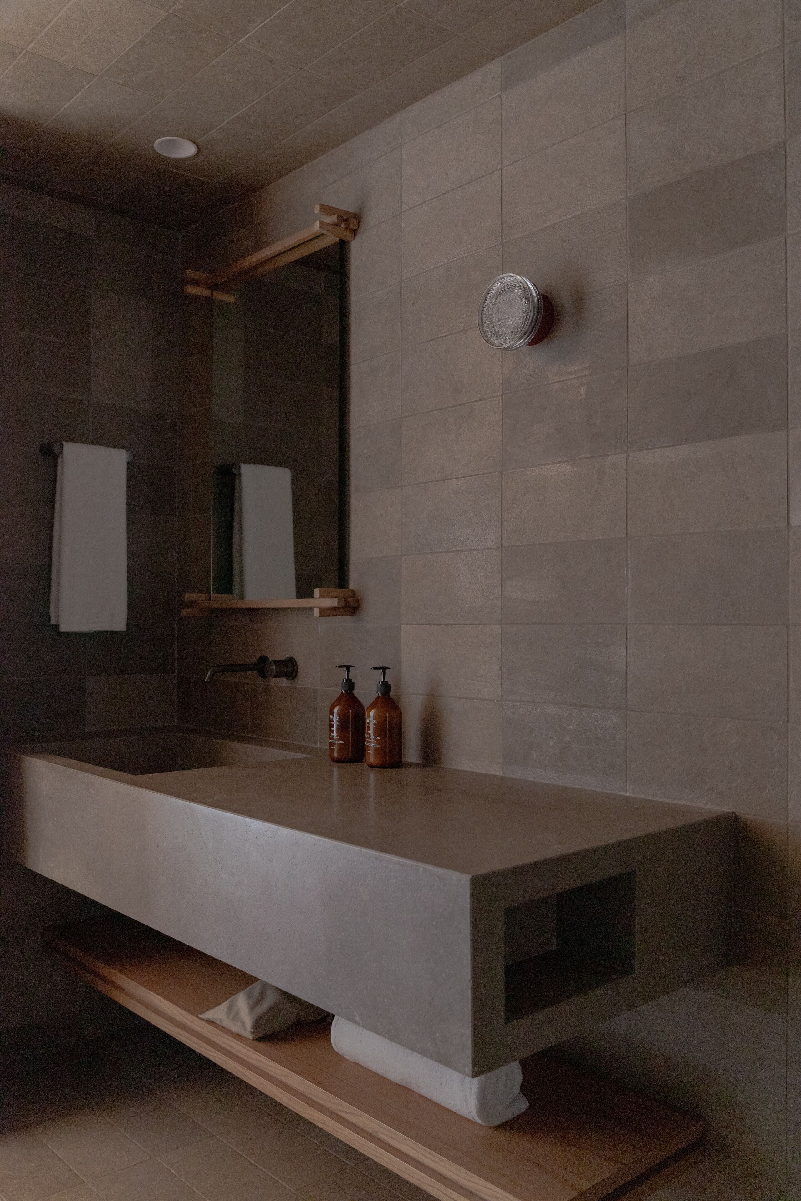 A modern bathroom with a large bathtub, a mirror, and a shelf with toiletries.