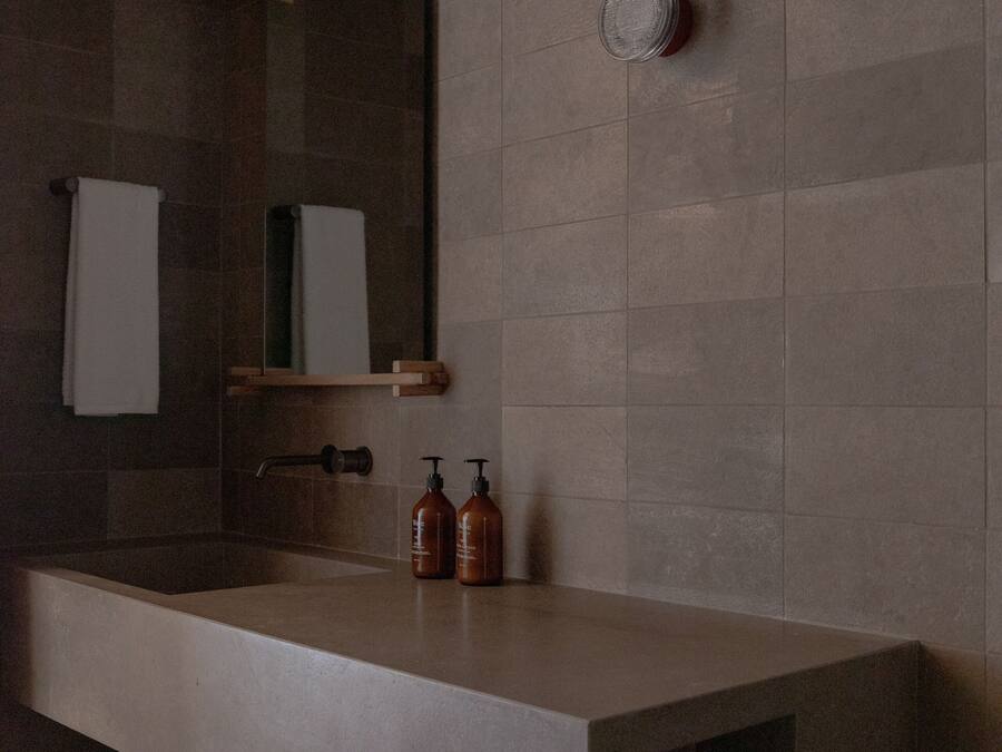 Une salle de bain moderne avec une grande baignoire, un miroir et une étagère contenant des articles de toilette.